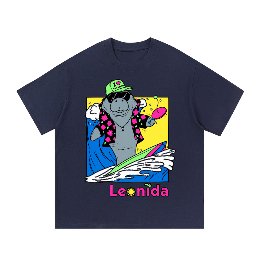 Playera oversized azul marino de algodon con estampado a color de un manati surfeando con gorra y camisa hawaiana, vista frontal