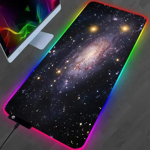 Mousepad extragrande con estampado de nebulosa y borde iluminado RGB sobre un escritorio
